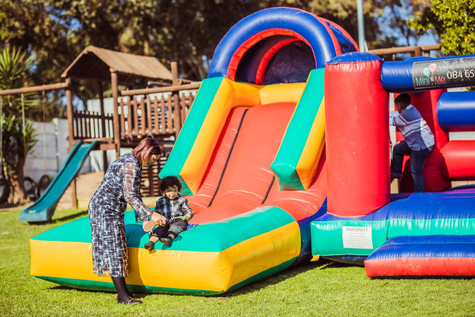 Children playing on the jumping castle and slide on the Mini & Me lawn