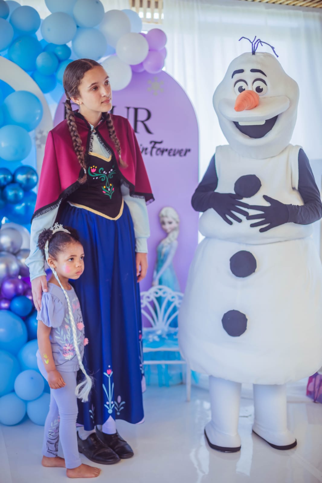 Anna and Olaf characters with excited party guests in the decorated venue